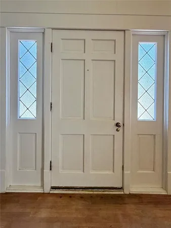 an empty room with wooden floor closet and windows