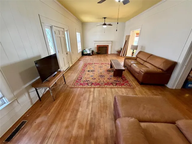 an empty room with wooden floor fireplace and windows