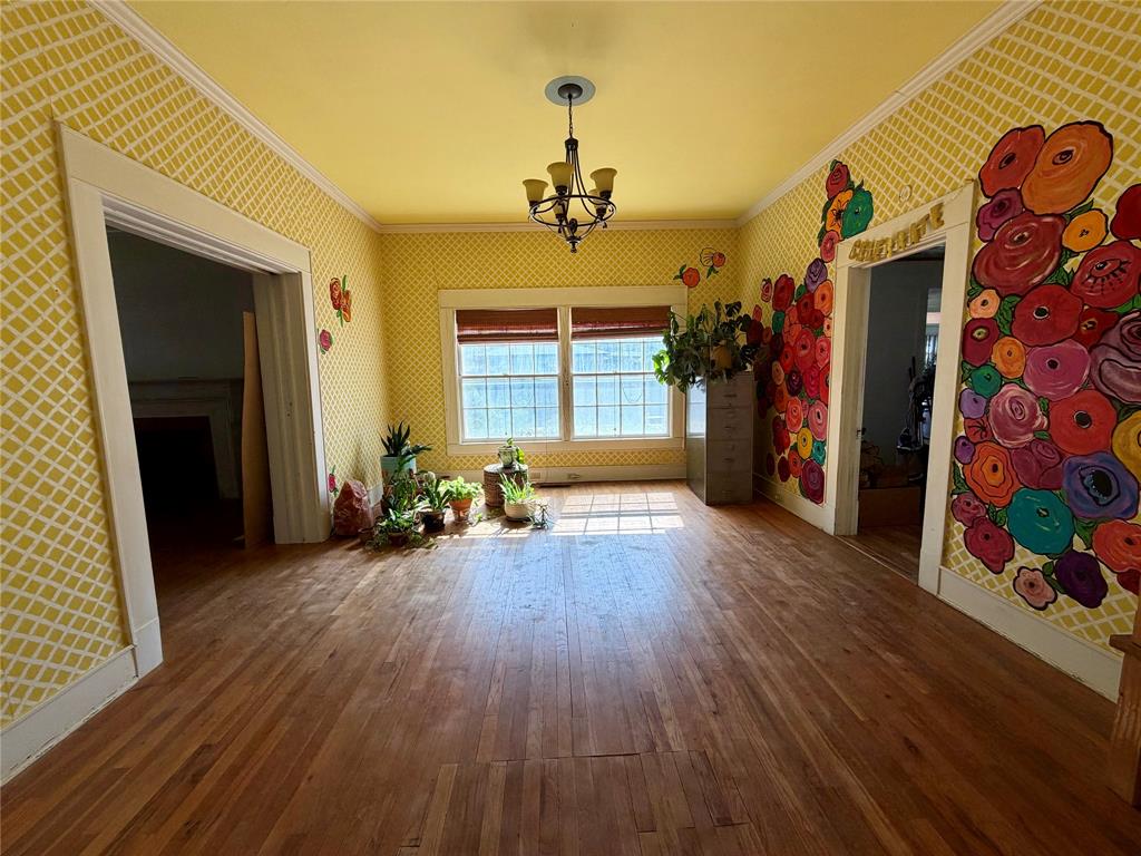 600 Mercer Street Quanah, TX 79252 - Photo 8 of 28 an empty room with wooden floor fireplace and windows