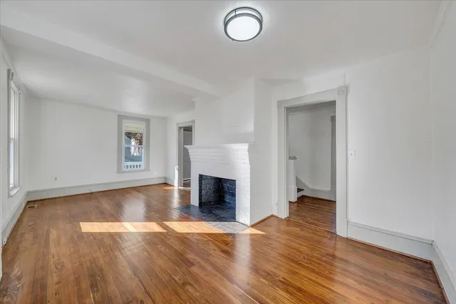 an empty room with wooden floor and fireplace