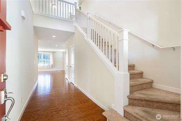 an empty room with wooden floor fireplace and windows