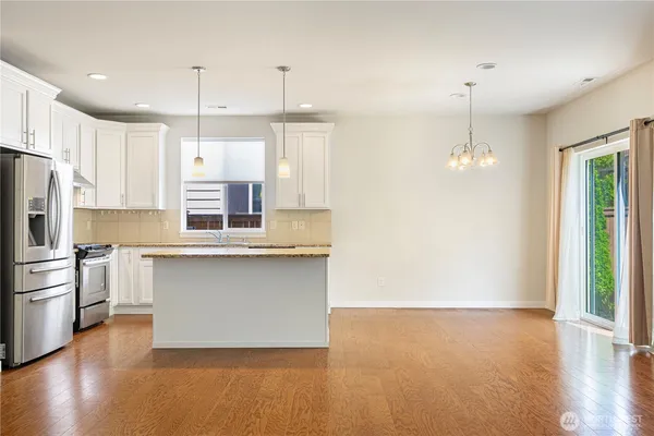 a kitchen with stainless steel appliances granite countertop a refrigerator a stove a sink and white cabinets