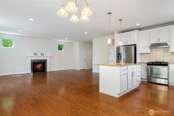 a view of an empty room with wooden floor and a kitchen