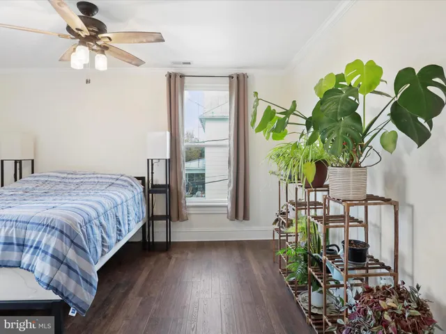 a bedroom with a bed table flowerpot and window