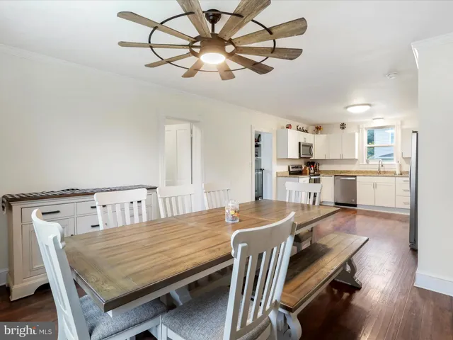 a dining room with wooden floor a chandelier a wooden table and chairs