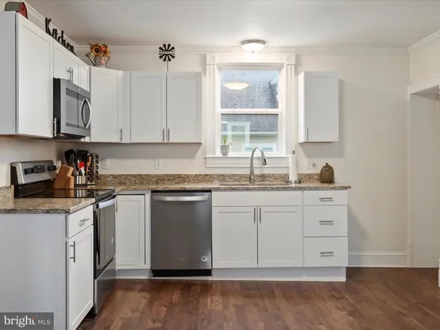 a kitchen with granite countertop a sink stainless steel appliances and cabinets