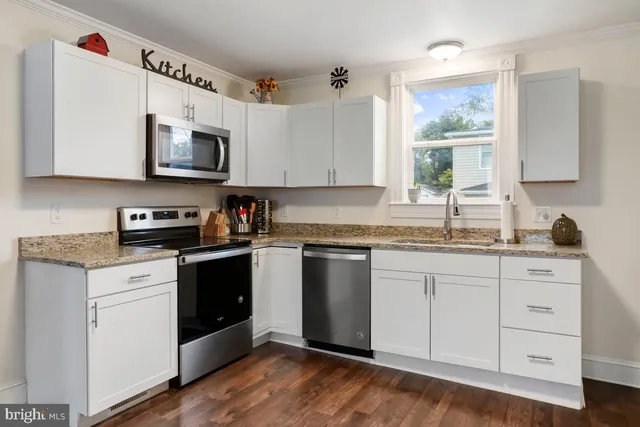 a kitchen with granite countertop a sink cabinets stainless steel appliances and a window