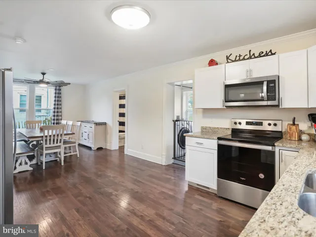 a kitchen with granite countertop a stove top oven a sink dishwasher a dining table and chairs with wooden floor