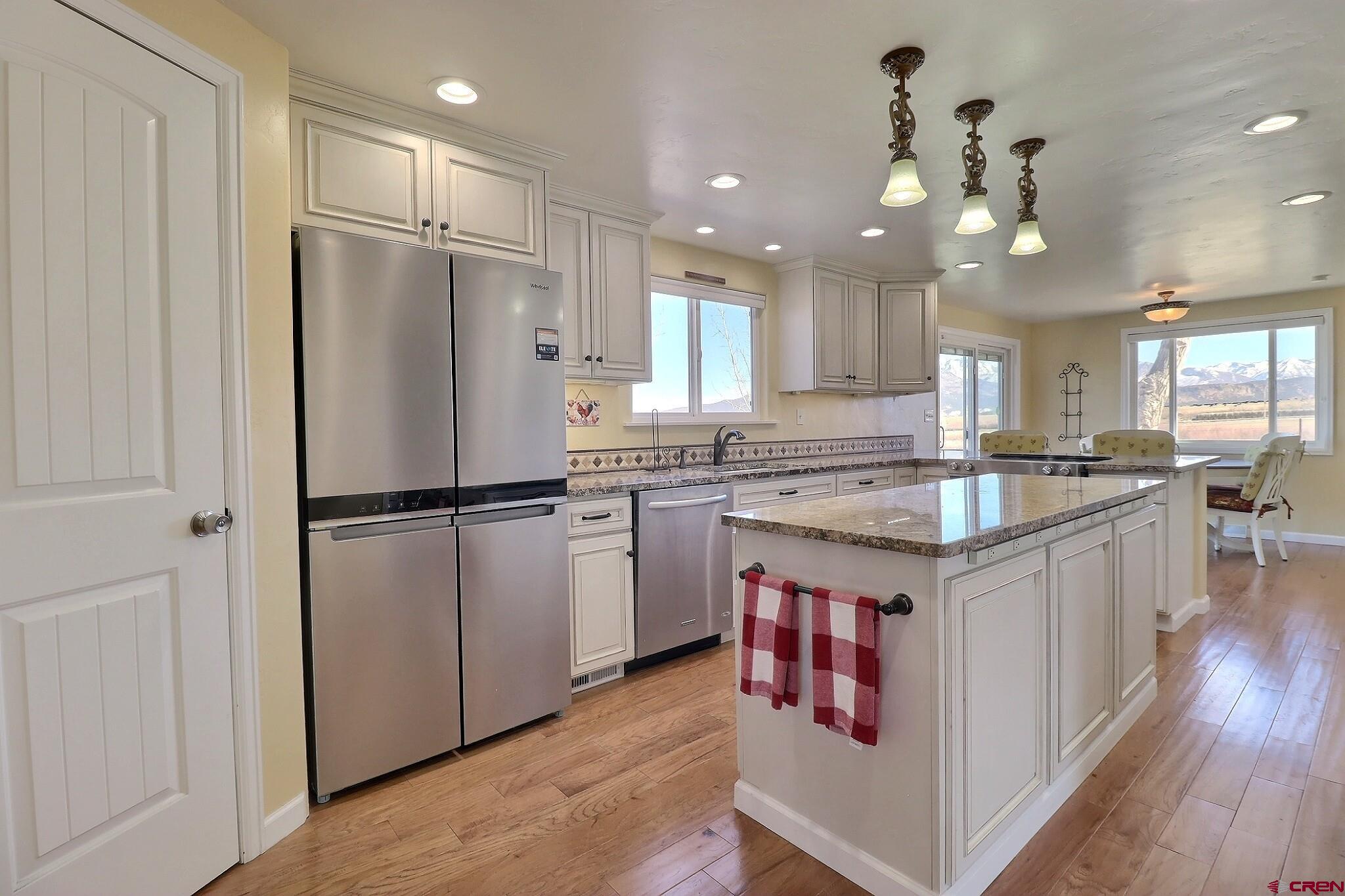 36557 Grandview Mesa Road Crawford, CO 81415 - Photo 10 of 45 a kitchen with kitchen island granite countertop a refrigerator a sink dishwasher a stove and white cabinets with wooden floor