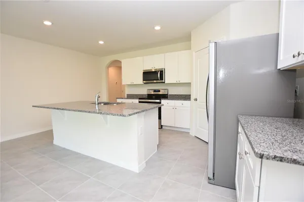 a kitchen with stainless steel appliances granite countertop a refrigerator a stove and a sink