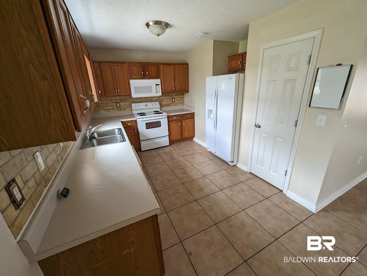 12971 Labradors Run Foley, AL 36535 - Photo 7 of 23 Kitchen featuring wood cabinetry, solid surface countertops, tile flooring, and a brick-style backsplash