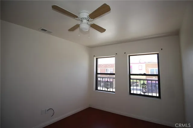 an empty room with windows and fan
