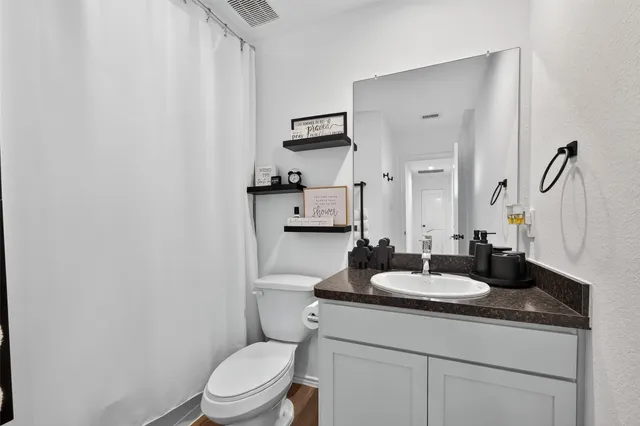 a bathroom with a granite countertop sink toilet a mirror and shower