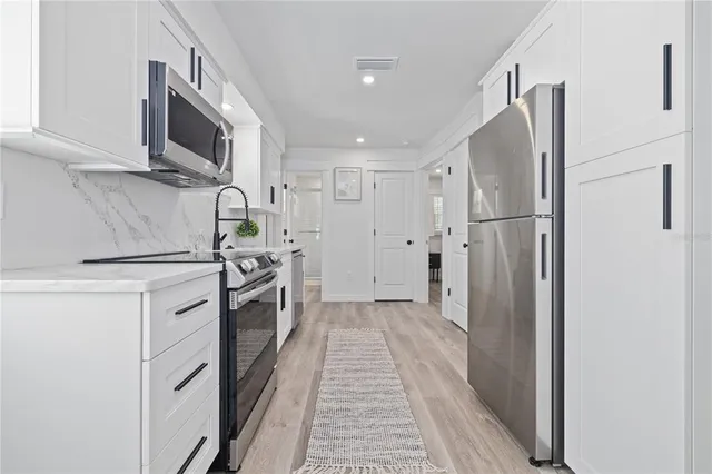 a kitchen with stainless steel appliances a refrigerator sink and microwave