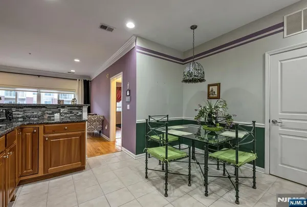 a kitchen with stainless steel appliances granite countertop a refrigerator a stove a microwave oven a dining table and chairs with wooden floor