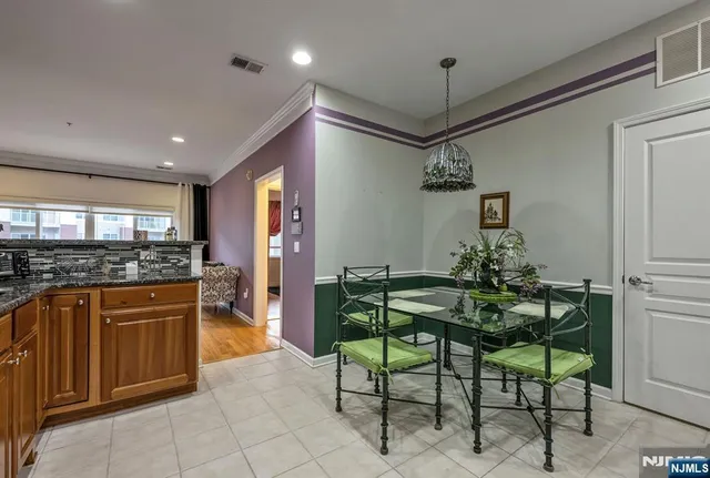 a kitchen with stainless steel appliances granite countertop a refrigerator a stove a microwave oven a dining table and chairs with wooden floor