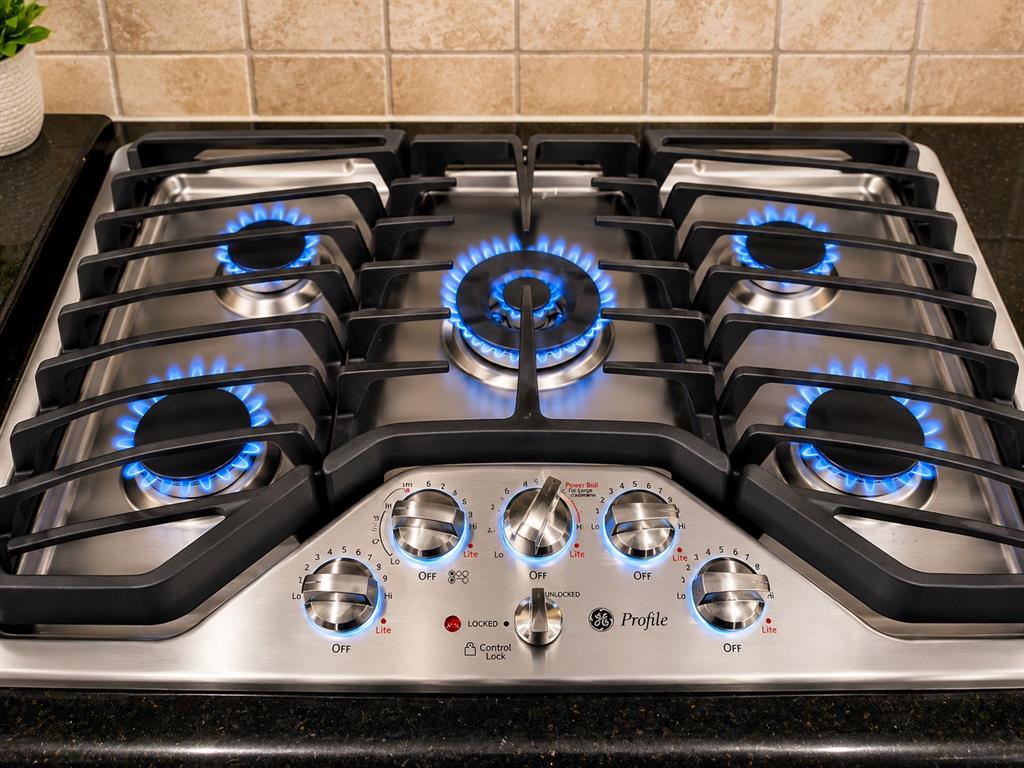 5708 Rickshaw Lane Plano, TX 75094 - Photo 13 of 28 Stainless steel gas cooktop with five burners and continuous grates, set into a dark countertop