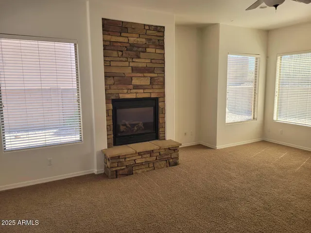 an empty room with windows and fireplace