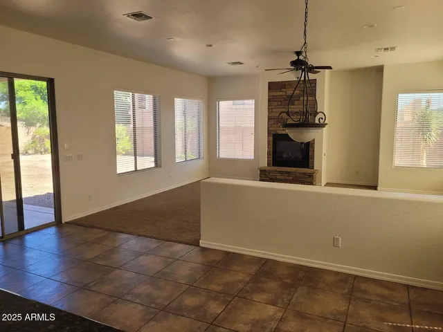 a view of an empty room with a window and kitchen view