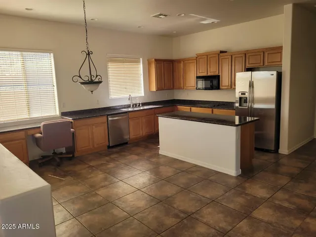 a kitchen with stainless steel appliances granite countertop a sink a stove a refrigerator a counter top space and cabinets