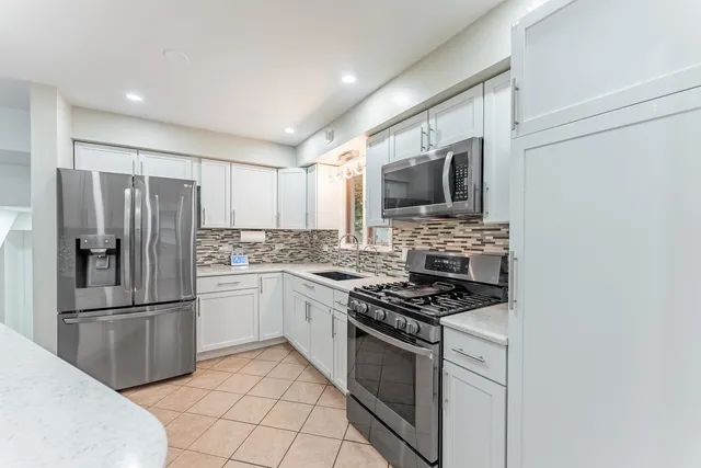 a kitchen with granite countertop a sink stove and refrigerator