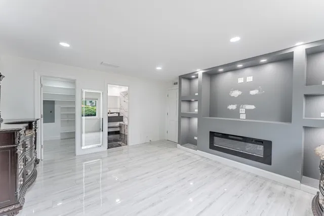 a view of empty room with kitchen and refrigerator