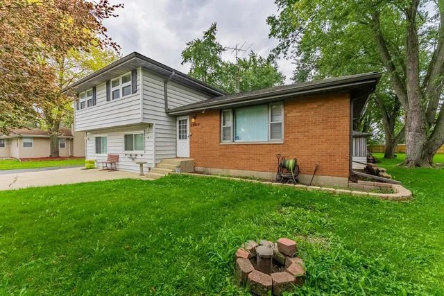 a backyard of a house with table and chairs plants and large tree