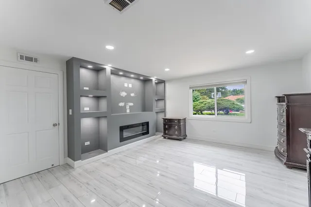 an empty room with windows and fireplace