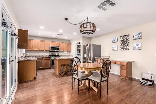 a kitchen with stainless steel appliances granite countertop a stove top oven a refrigerator a sink and dishwasher with wooden floor