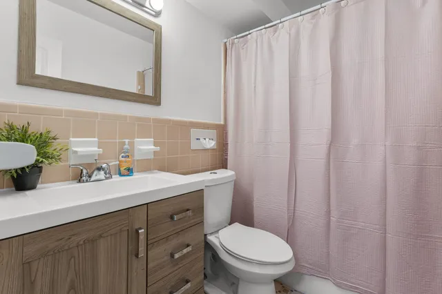 a bathroom with a granite countertop sink and a toilet