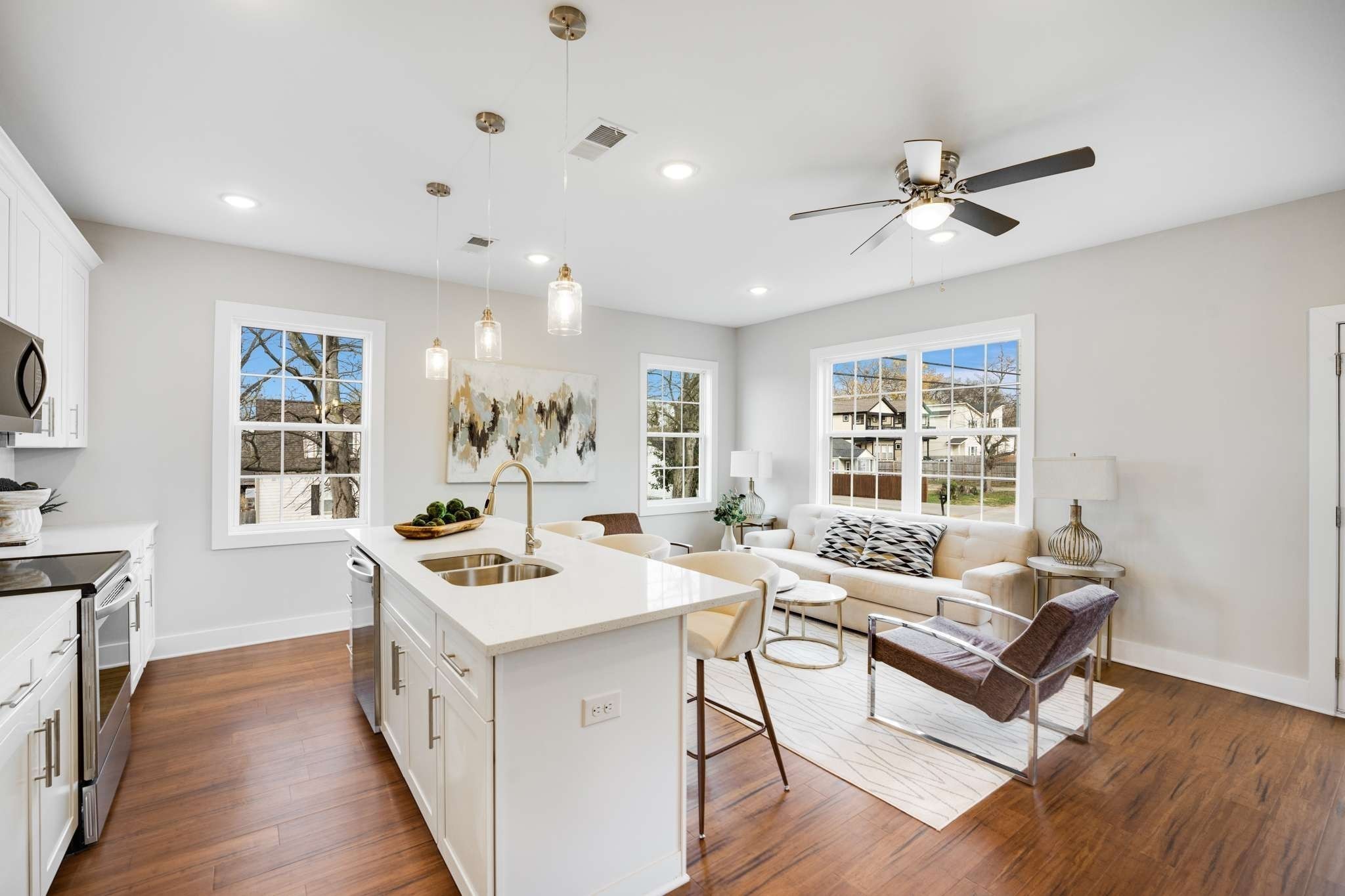 a living room with stainless steel appliances kitchen island hardwood floor and a window