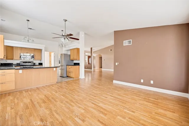 a large kitchen with stainless steel appliances kitchen island granite countertop a refrigerator a stove a sink dishwasher and a fireplace with wooden floor