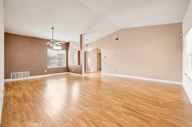 a view of an empty room with window and wooden floor