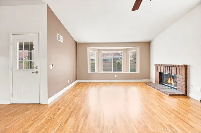 a view of an empty room with window and wooden floor