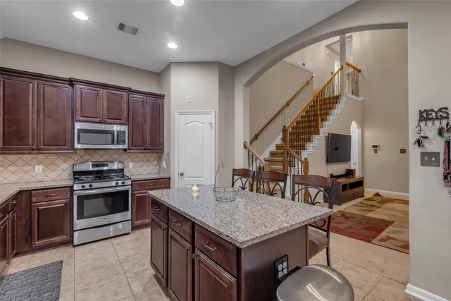 a kitchen with kitchen island granite countertop a stove a sink and a refrigerator