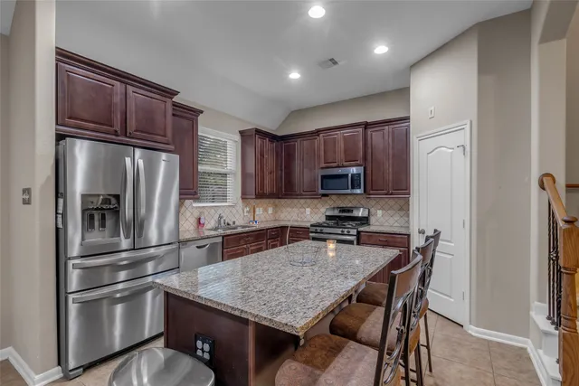 a kitchen with stainless steel appliances granite countertop a refrigerator and a stove top oven