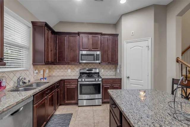 a kitchen with stainless steel appliances granite countertop wooden cabinets stove top oven and sink