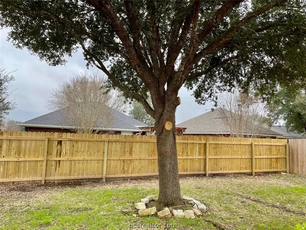 a view of backyard with table and chairs and wooden fence
