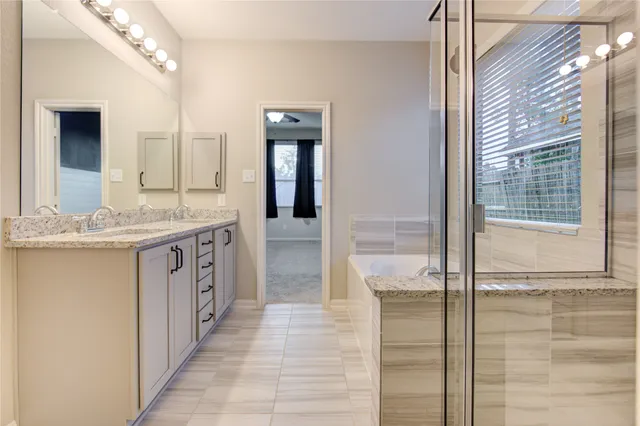 a bathroom with a granite countertop sink a mirror and a shower