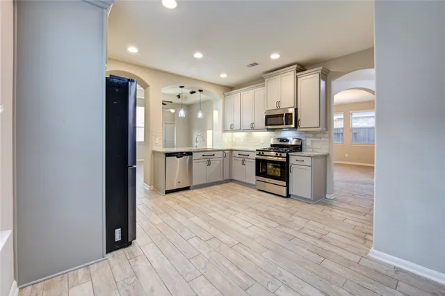 a kitchen with stainless steel appliances granite countertop a stove top oven a sink and a refrigerator
