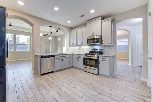 a large kitchen with stainless steel appliances granite countertop a stove a sink dishwasher and a refrigerator with wooden floor