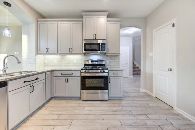 a kitchen with granite countertop a stove sink and cabinets