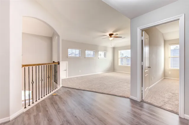 an empty room with wooden floor and windows