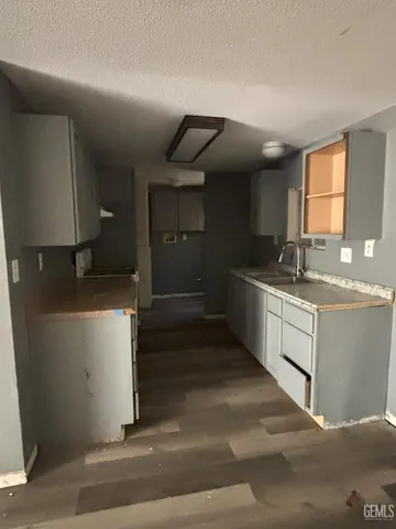 a kitchen with granite countertop a stove a sink and a white cabinets