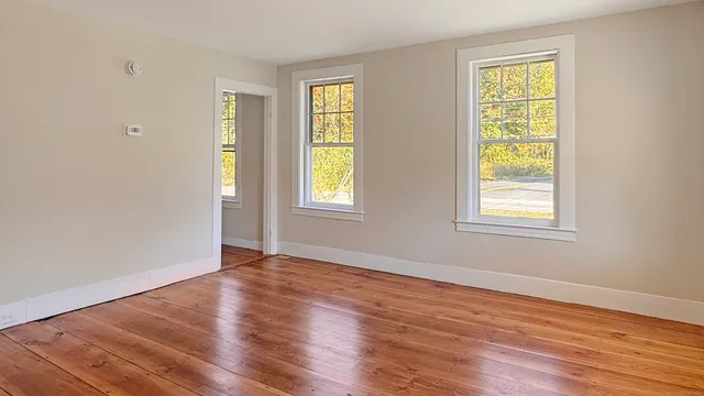 a view of an empty room with wooden floor and a window