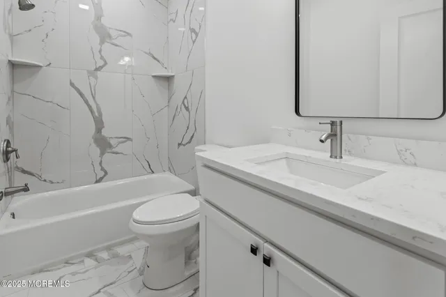 a bathroom with a granite countertop toilet sink and mirror