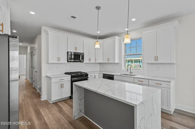 a kitchen with stainless steel appliances granite countertop a sink a stove a refrigerator cabinets and wooden floor