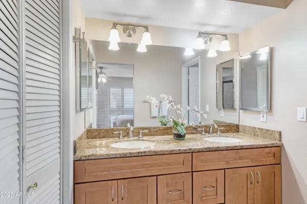 a bathroom with a granite countertop double vanity and a mirror