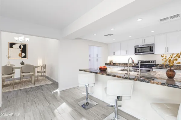 a kitchen with stainless steel appliances granite countertop a sink a stove a dining table and chairs