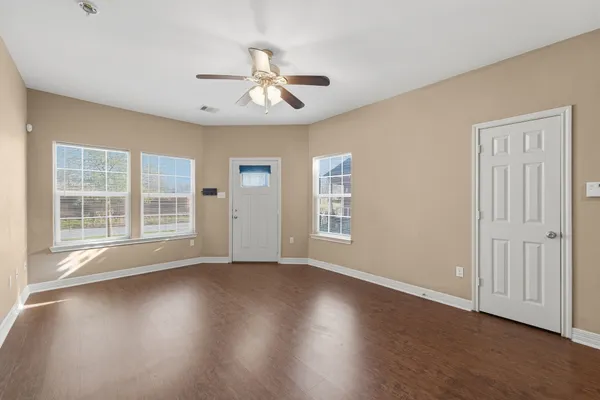 a view of an empty room with wooden floor and a window